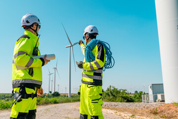 Two technicians discuss wind turbine maintenance at a renewable energy site during a clear sunny day