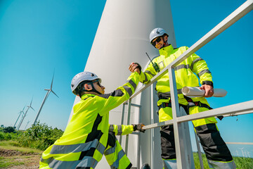 Wind energy technicians perform maintenance on wind turbine in a sunny environment
