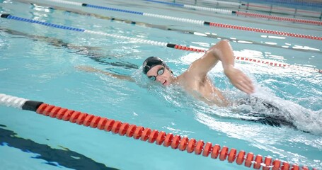 Swimming in pool, male athlete performing freestyle stroke during swim practice