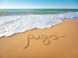 August word written on sea sand shore beach at day.