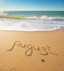 August word written on sea sand shore beach at day.