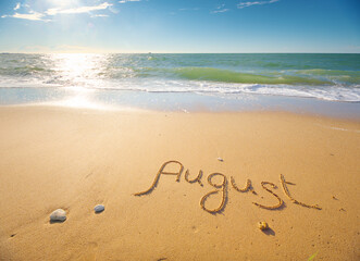 August word written on sea sand shore beach at day.
