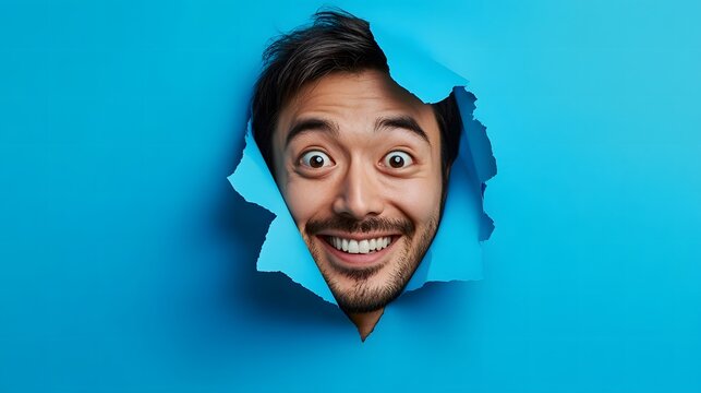 Man Making Funny Face through Blue Torn Paper / 青い破れ紙から変顔をする男性
