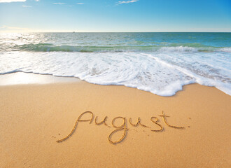 August word written on sea sand shore beach at day.