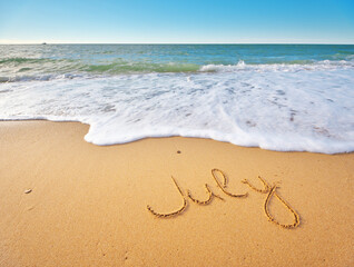July word written on sea sand shore beach at day.
