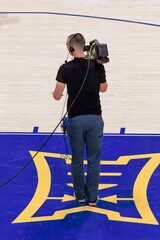 Videographer Filming a College Basketball Game Courtside