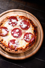Pizza with salami and mozzarella cheese. Wooden background. Soft focus. Close up.	