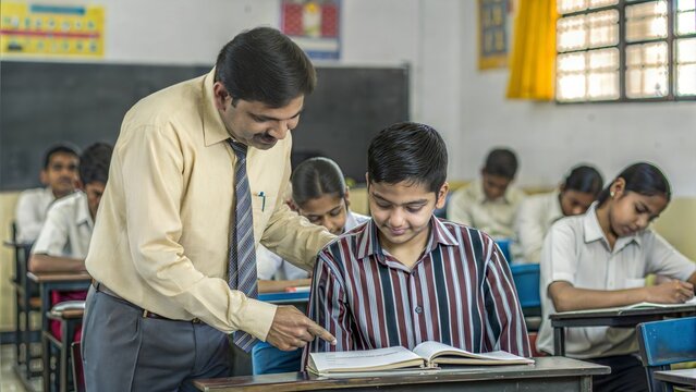 Teacher and Student Interaction : Indian teacher helping a student in a classroom setting.
