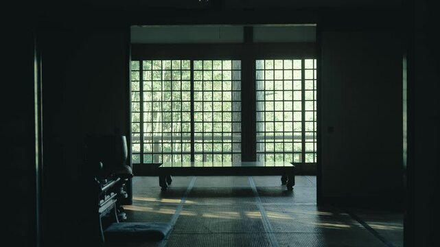 日本の寺院の和室の窓の向こうに風になびく竹林が見える