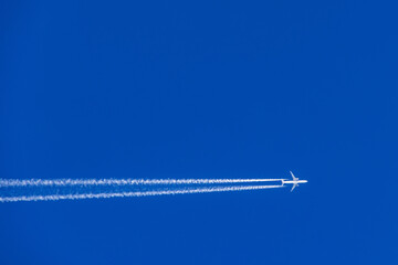 Aeroplane with white vapor trails flying on a blue sky