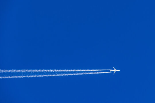 Aeroplane with white vapor trails flying on a blue sky