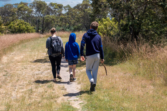 Family of Three people walking on a grassy bush trail in Australia