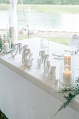 Sweetheart table at outdoor wedding with white linens and candles.