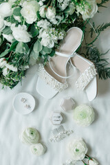 Bridal accessories flatlay of bouquet, pearl heels, and jewelry.