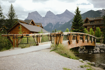 Fototapeta premium Wooden bridge over water with mountain and downtown Canmore backdrop