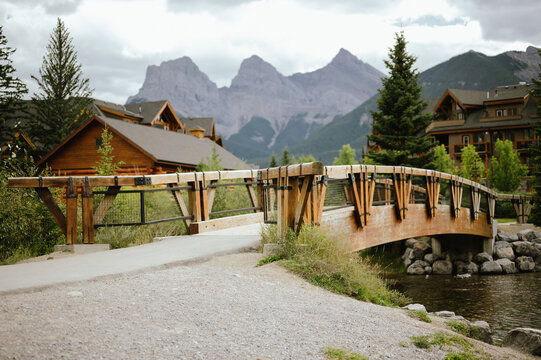 Wooden bridge over water with mountain and downtown Canmore backdrop