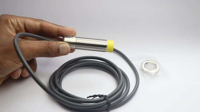 Proximity sensor of NPN and capacitance type held in the hand on a white background