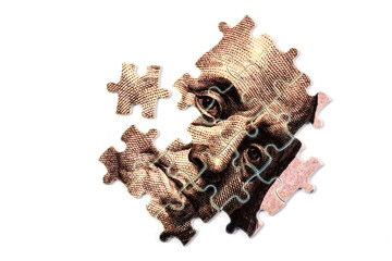 A fragment of a 100 US dollar bill assembled from puzzles with a portrait of Benjamin Franklin on a white background