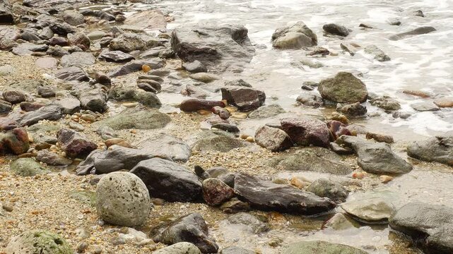 Foamy Waves Crashing on a Rocky Shoreline: A Close-Up View of the Ocean&rsquo;s Dynamic Movement, Showcasing the Natural Power and Beauty of Water Interacting with Rugged Coastal Rocks