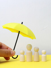 two wooden figures of a man and a woman covered by an umbrella. the concept of husband and wife protection