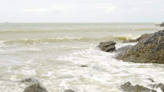 Foamy Waves Crashing on a Rocky Shoreline: A Close-Up View of the Ocean&rsquo;s Dynamic Movement, Showcasing the Natural Power and Beauty of Water Interacting with Rugged Coastal Rocks