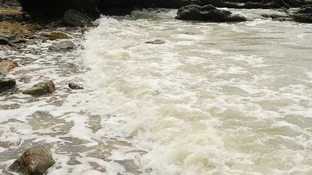 Foamy Waves Crashing on a Rocky Shoreline: A Close-Up View of the Ocean&rsquo;s Dynamic Movement, Showcasing the Natural Power and Beauty of Water Interacting with Rugged Coastal Rocks