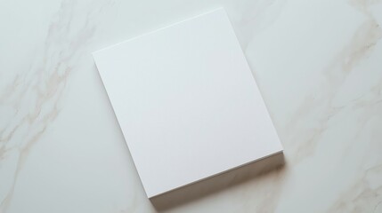 Blank white paper on a marble background, ideal for mockups or design presentations with natural lighting.