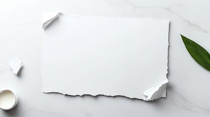 Fototapeta premium Torn white paper on marble with green leaf, ideal for background or mockup design, evokes simplicity and minimalism.