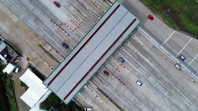 Overhead view of cars passing through a highway toll booth. Smooth traffic flow, clear day.