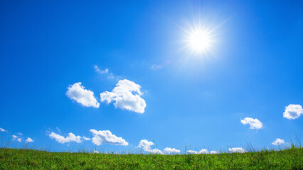 Obraz premium Bottom up view of blue sky with shining sun White fluffy clouds on a blue sky in spring season