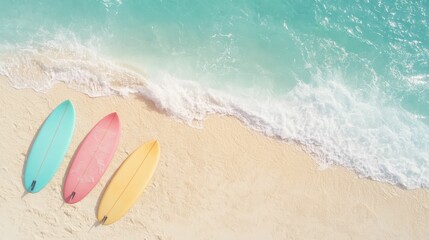 Obraz premium Three colorful surfboards on a sandy beach, with gentle waves lapping at the shore under a bright blue sky.