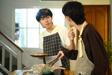 Happy gay couple enjoys cooking together in their home kitchen
