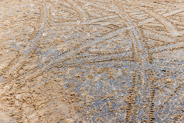 Crossing tire tracks go over wet snowy road