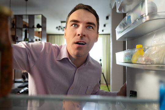 Hungry adult Caucasian businessman entrepreneur man after work open empty refrigerator. POV point of view from inside fridge