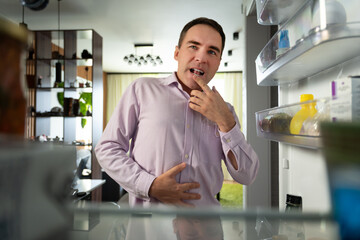 A businessman looks for food in the fridge and chooses what to eat. Man hungry guy open empty...