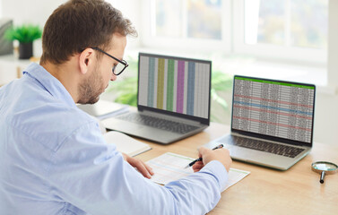 Portrait of a busy confident business man accountant sitting at the desk and working on a laptop...