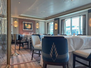 Art Deco interior design style furniture, carpets and paneling onboard modern ocean liner cruiseship cruise ship main dining room restaurant with flower deco and set tables