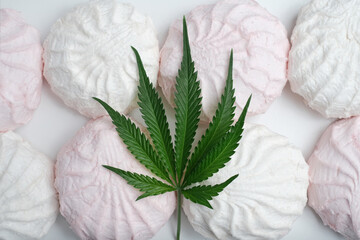 CBD and THC marshmallows with cannabis leaves lie on a plate. Marijuana sweets concept