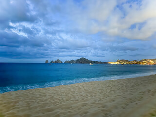 Twilight paints the sky above the shimmering sea, where the El Arco rocks stand tall. A gentle breeze whispers secrets along the sandy shore, in Cabo San Luca, Mexico.