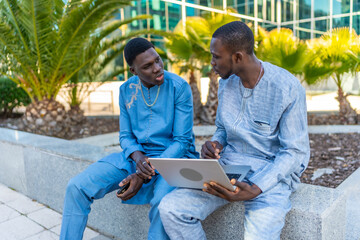 Senegalese businessmen wearing traditional dashiki using laptop outdoors