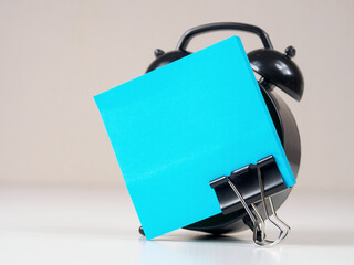 A blank reminder sticker and alarm clock inspire productivity, creating space for ideas and plans.