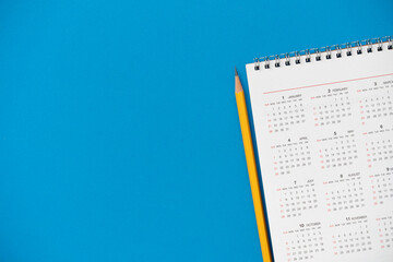 close up of calendar and pencil on the blue table background, planning for business meeting or travel planning concept