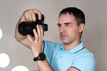 Photographer holding mirrorless camera for check his photo in selective focus. paparazzi, the photographer watches the subject through the camera. a handsome photographer with a telephoto lens