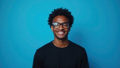 Obraz premium A young black African American man wearing eyeglasses and a black sweater is on blue studio background