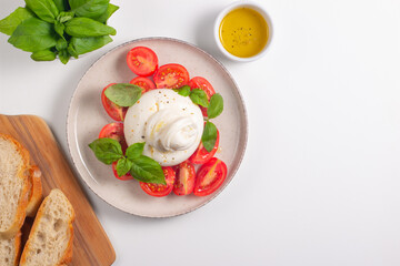 Delicious Italian caprese salad with sliced mozzarella, tomatoes, basil, and bread on background. 