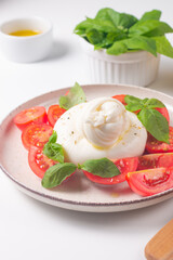 Delicious Italian caprese salad with sliced mozzarella, tomatoes, basil, and bread on background. 