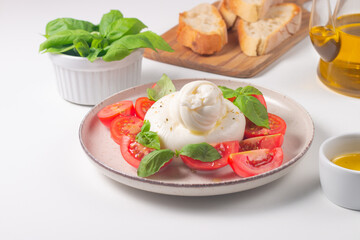 Delicious Italian caprese salad with sliced mozzarella, tomatoes, basil, and bread on background. 