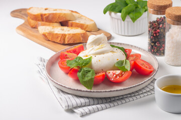 Delicious Italian caprese salad with sliced mozzarella, tomatoes, basil, and bread on background. 