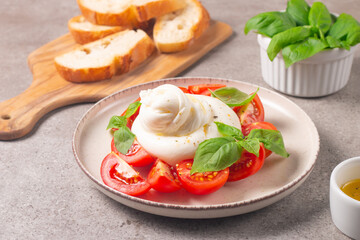 Delicious Italian caprese salad with sliced mozzarella, tomatoes, basil, and bread on background. 