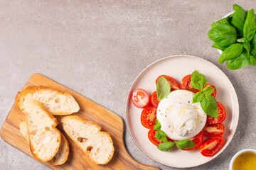 Delicious Italian caprese salad with sliced mozzarella, tomatoes, basil, and bread on background. 